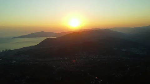 4K aerial drone flight forward at sunset over mountains and coastal city Stock Footage 315207043