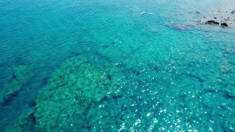 4K aerial drone flight over clear turquoise sea with sunlight reflections and Stock Footage 331534845