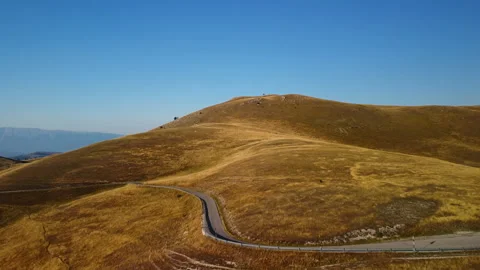 4K aerial drone forward ascent over morning yellow-orange hills with road below Stock Footage 315197852