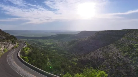 4k aerial drone shot of an empty road amongst mountains on a sunny day Stock Footage 276759473