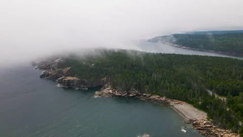 4K Aerial Drone stationary view of clouds rolling in over pine tree peninsula Stock Footage 240297553