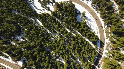 4K Aerial Drone Top Down fly over road bend in snowy pine forest Stock Footage 241140796
