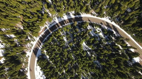 4K Aerial Drone Top Down Rise over road bend in snowy pine forest Stock Footage 241140798