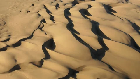 4K aerial drone view flying by beautiful wavy sand dunes in golden sunset light Video stock 134475485