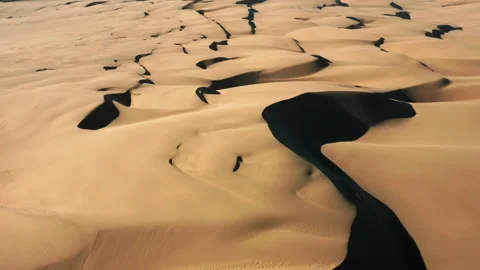 4K aerial drone view flying by beautiful wavy sand dunes in golden sunset light Video stock 134568441