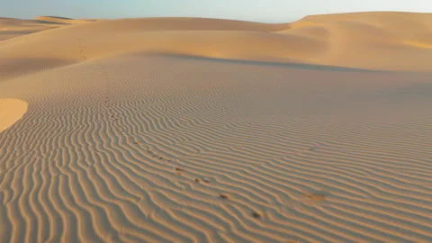 4K aerial drone view flying by beautiful wavy sand dunes in gentle sunrise light 스톡 동영상 134572030