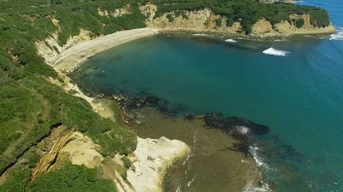 4K Aerial drone view over water flying around cliffs looking a white sand beach 動画素材 90957722