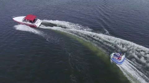 4k aerial fast boat pulls tube in circle Stock Footage 64987693