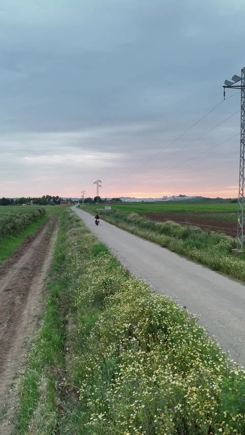 4K Aerial fixed view of a motorcycle driving away on a rural road Spain Stock Footage 336205396