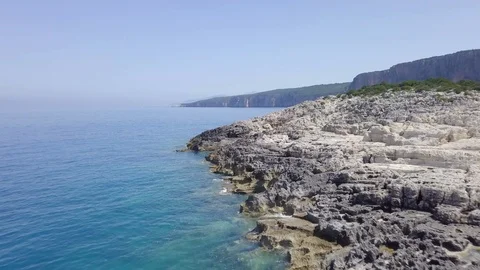 4K aerial forward low over rugged rocky coastline Greek island mediterranean sea Stock Footage 94156899