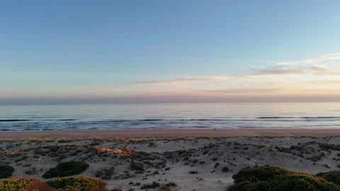 4K Aerial: Panoramic backward shot of Enebrales beach and forest at sunset. Stock Footage 333637582