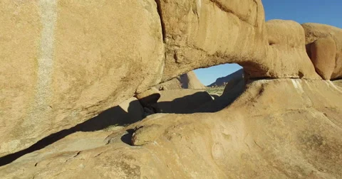 4K aerial shot flying through the granite arch of the Spitzkoppe mountains Stock Footage 64698043