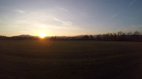 4K: Aerial shot of sun setting over a meadow Stock Footage 74884364