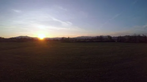 4K: Aerial shot of sun setting over a meadow Stock Footage 74886003