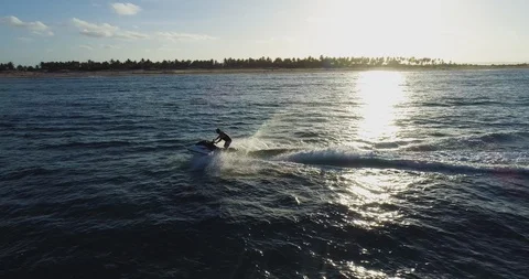 4K aerial side view of man having fun riding a Jet Ski in the ocean with the sun Stock Footage 102769526
