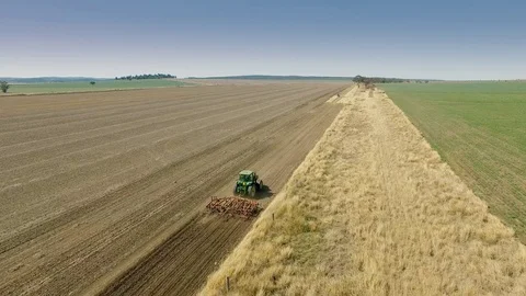 4K Aerial Of Tractor Pulling A Plough Through Soil Stock Footage 83607537