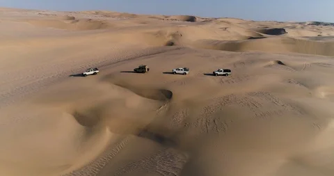 4K aerial view of 4x4 vehicles driving along the picturesque sand dunes of the Stock Footage 95259786