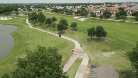 4K Aerial View: Busy Golf Carts on Green with Luxurious Neighborhood Backdrop Video stock 246922357