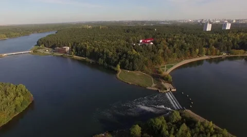 4K aerial view – flight over dam through the river with a green city district ne Stock Footage 56165192