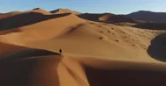 4K Aerial View Of Male Tourist Walking Over The Sand Dunes In The Namib Desert Stock Footage