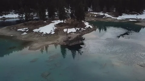 4K Aerial View over Mountain lake in autumn, winter with snow and forest and way Stock Footage 90776142
