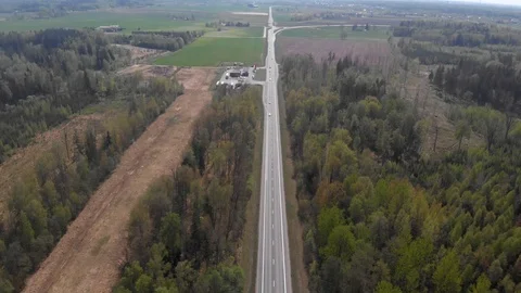 4k aerial view of road in middle of forest strip with moving trafic in daylight Stock Footage 112874656