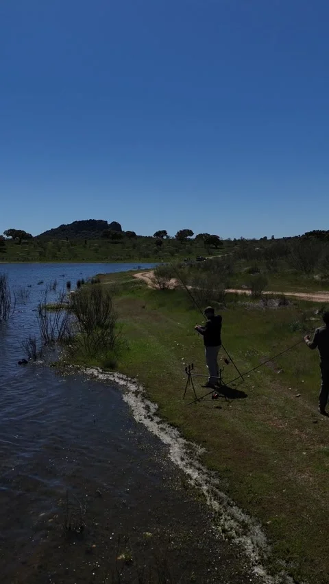4K Aerial view tracking backward from a fisherman preparing gear at lake Stock Footage 336205444