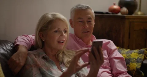 4K Affectionate couple relaxing at home at night, looking at internet on phone Stock Footage 84165376