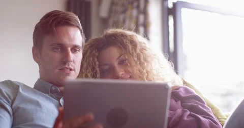 4K Affectionate couple relaxing on the sofa, looking at computer tablet Stock Footage 114658216