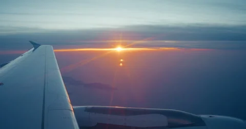 4k Airplane Window View of Wing and Engine in Golden Dusk Light Over the Sea Stock Footage 343596276