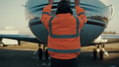 4K Airport worker signaling to airplane pilot on the runway. Stock Footage
