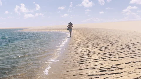 4k of alone young beautiful woman walking on beautiful white beach with beach ba Stockbeeldmateriaal 199627341