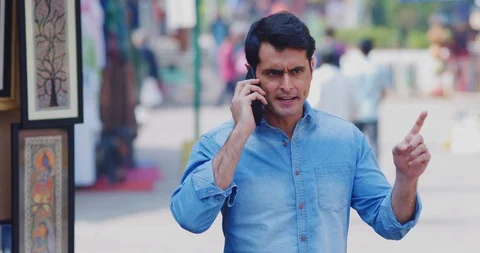 4K Angry &amp; stressed man arguing during phone call in Indian street market Stock Footage 103345069