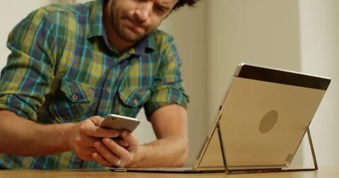 4K Annoyed man using computer at home &amp; making angry phone call. Slow motion. Stock Footage 80464811