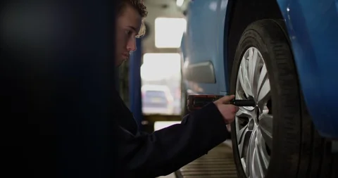 4K Apprentice garage mechanic changing a tyre during car service &amp; repairs Stock Footage 113094125