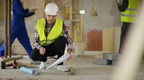 4K Architect checking the plans at construction site with building crew working Stock Footage 65105772