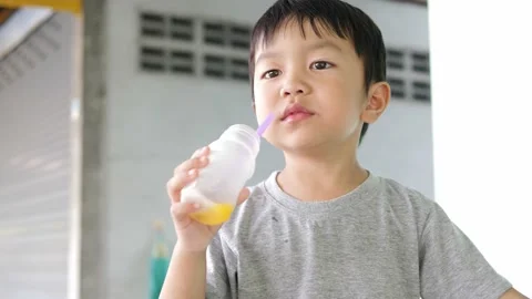 4K Asian child boy drinking orange juice from bottle with delicious funny face. Stock Footage 145753941