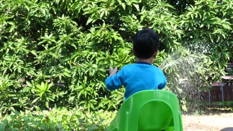 4K Asian child boy making beautiful rainbow by water splash and sunlight Video stock 145753632