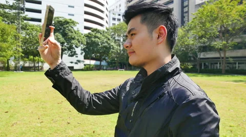4k Asian Man try to self portrait photograph with smart phone in the garden. Stock Footage 61631697