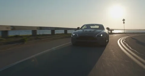 4K Aston Martin Cruising Down Empty Highway By the Water (Version 1) 库存影片 111664051