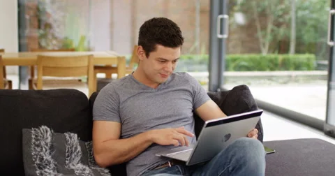 4k, An attractive man working from home on his touchscreen laptop. Stock Footage 68572069
