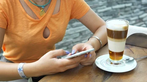 4K Attractive young female using her phone and drinking from a coffee cup at a Stock Footage 91970982