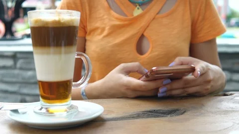 4K Attractive young female using her phone and drinking from a coffee cup at a Stock Footage 91971114