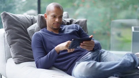 4K Attractive young man with computer tablet shopping on the internet at home Stock Footage 74368073