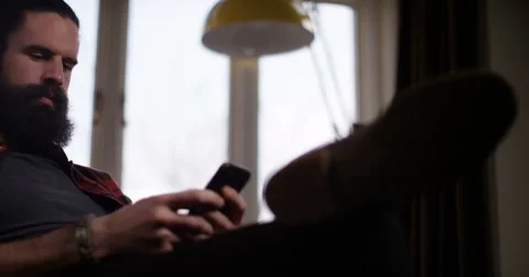 4k, Attractive young man texting with cell phone at kitchen table at home. Stock Footage 61741114