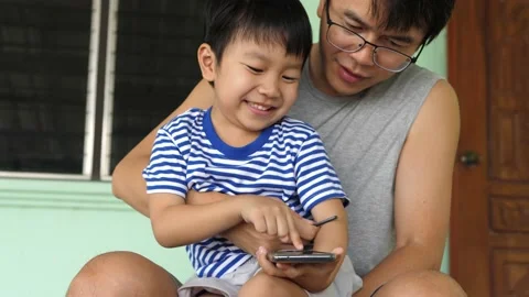 4K Authentic son touch screen on smartphone with cute face with father. Stock Footage 154753186