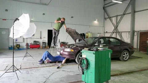   4K. Backstage photographing process of repair car team. Mechanic under car Stockbeeldmateriaal 75463490