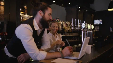 4K Bar Owner Working On Laptop &amp; Discussing Business Plan With Female Colleague Stock Footage 75800950
