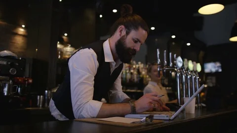 4K Bar Owner Working On Laptop With Female Employee Working In Background Stock Footage 75802033