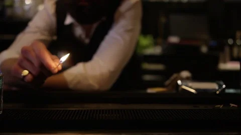 4K Barman Using A Match To Set Light To Row Of Shot Glasses With Clear Liquor 動画素材 75629633